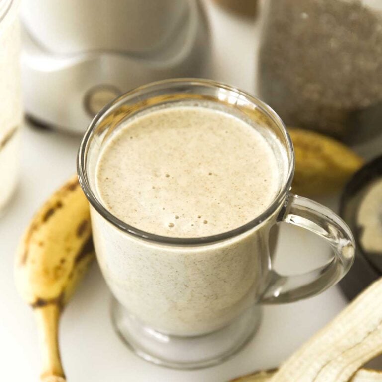High-protein banana smoothie with almond butter next to a banana.