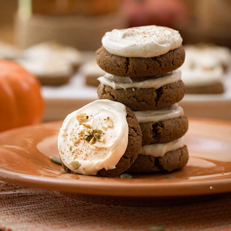 A stack of cream cheese pumpkin cookies on an orange plate.