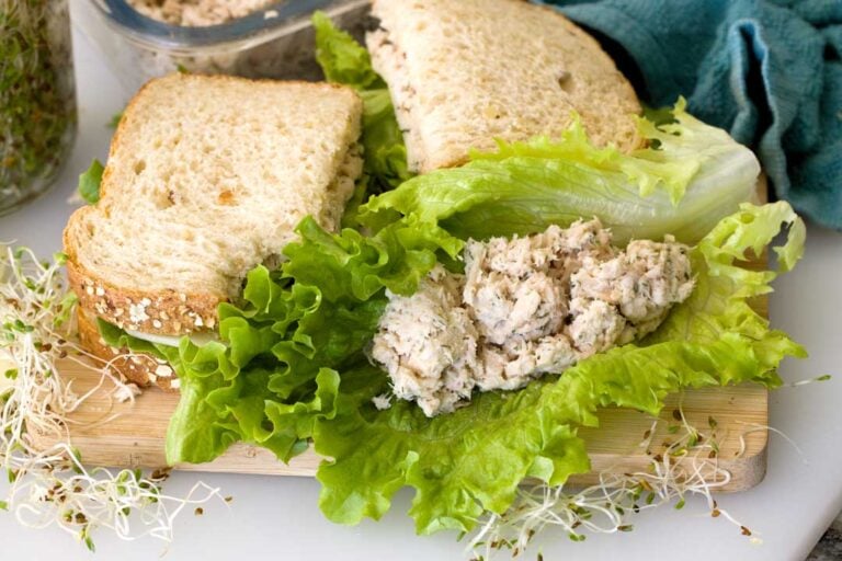 A scoop of tuna salad in a lettuce wrap next to a sandwich.