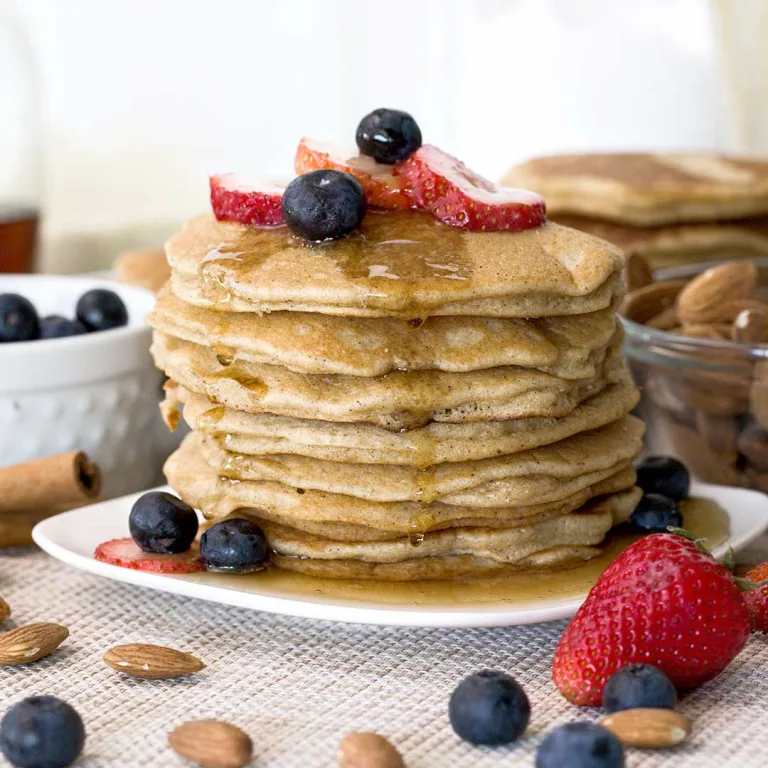 A stack of fluffy almond flour pancakes with maple syrup on top.