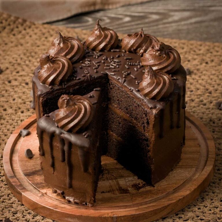 Gluten-Free Triple Chocolate Cake on a wooden cake plate.