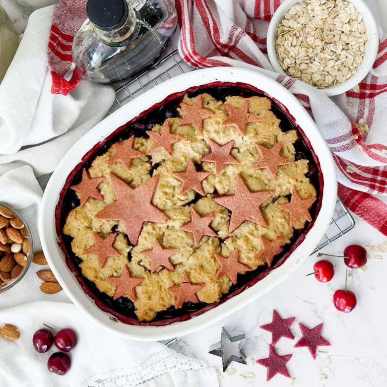 A star-spangled gluten-free berry cobbler with red stars on top in a white baking dish.