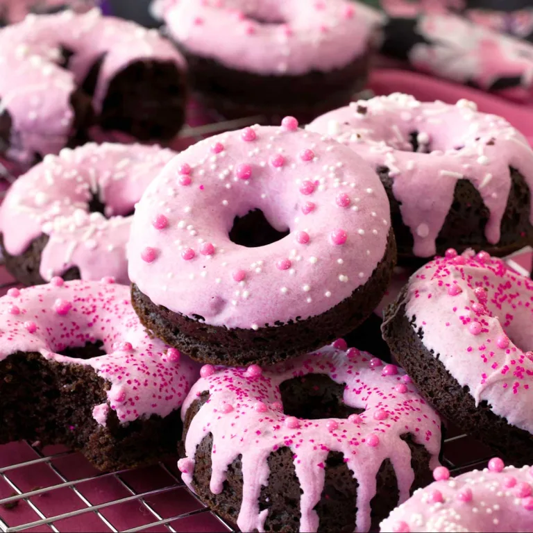 Stack of gluten-free chocolate donuts with white chocolate glaze covered in sprinkles.