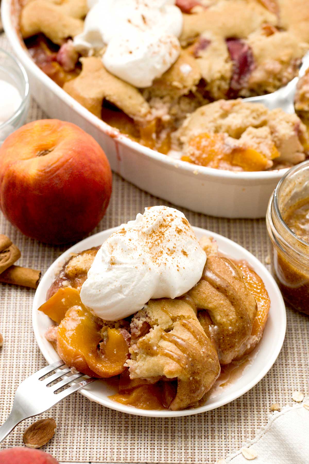 Gluten-free peach cobbler with oat and almond flour and whipped cream on top.
