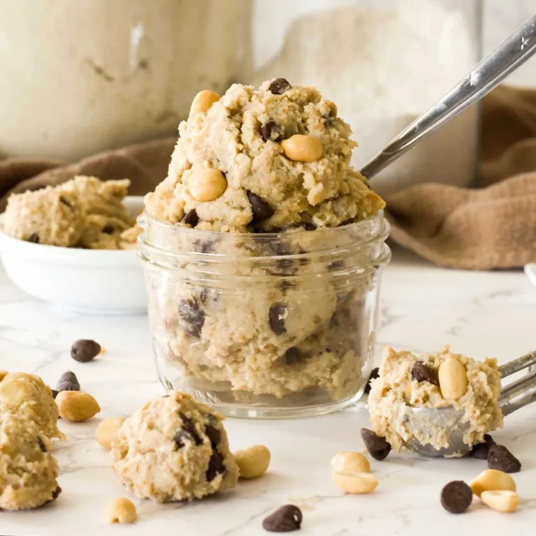 A small mason jar full of edible peanut butter cottage cheese cookie dough with chocolate chips and a cookie scoop.