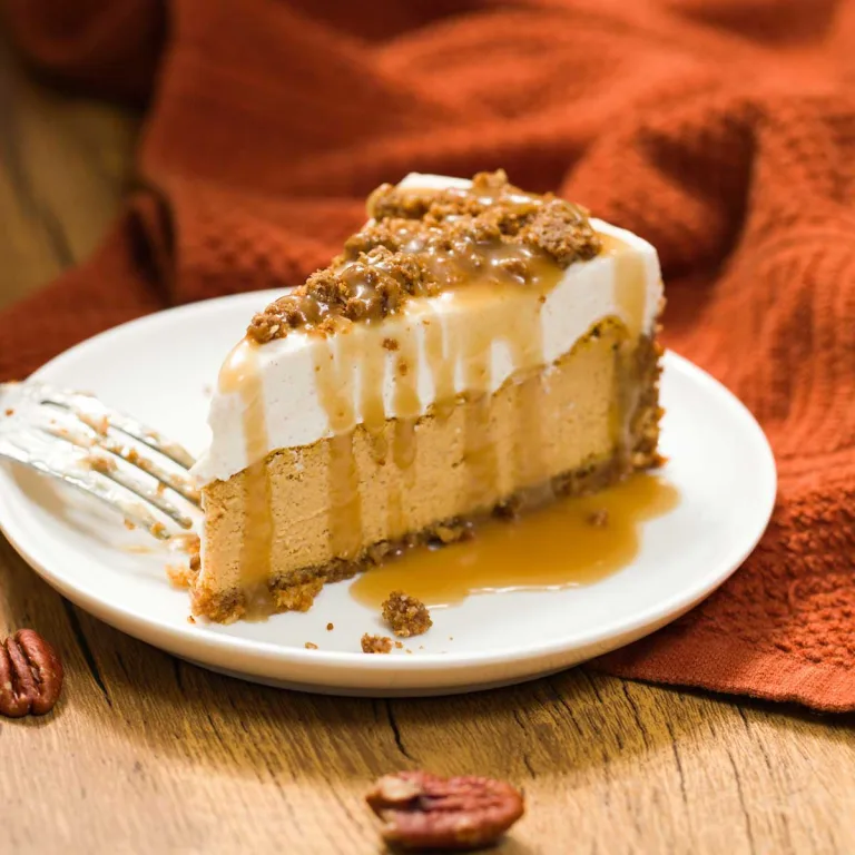 A slice of Olive Garden pumpkin cheesecake with layers of pumpkin, cream, caramel and pecan crumble on top.