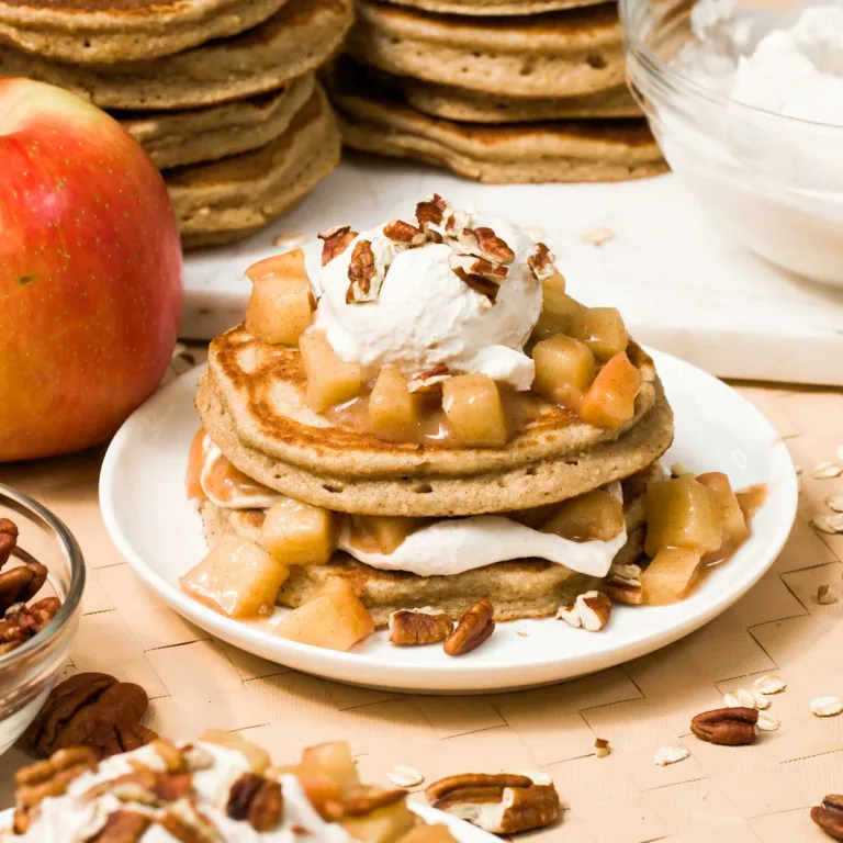 A stack of gluten-free apple cinnamon pancakes with apples and maple-sweetened Greek yogurt on top.