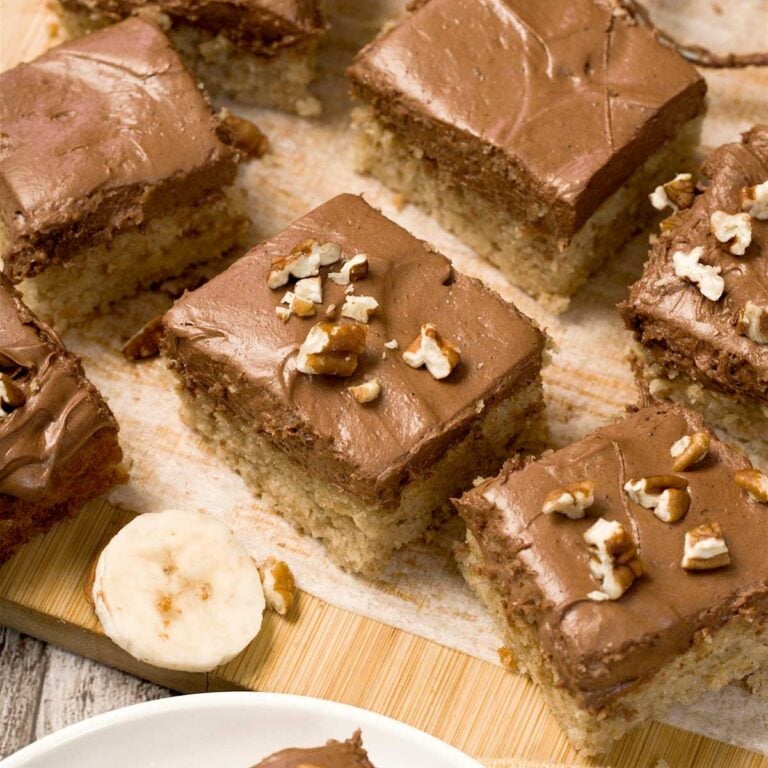 Gluten-free banana cake with chocolate cream cheese frosting cut into squares.
