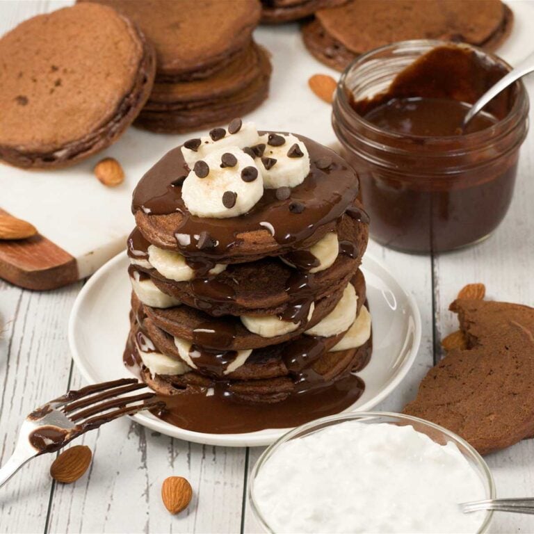 Stack of chocolate protein powder pancakes with cottage cheese on a plate.