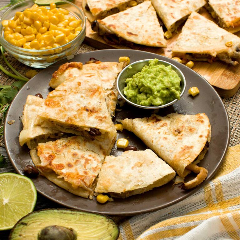 Sliced corn flour tortilla quesadillas with carnitas, black beans, and corn on a plate.