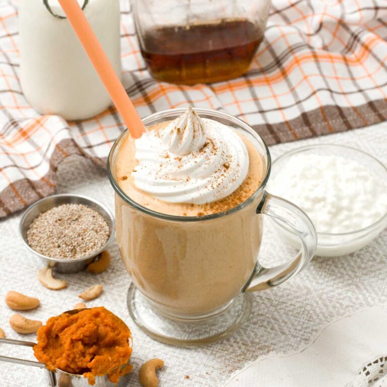 Glass with pumpkin protein smoothie with cottage cheese and an orange straw.