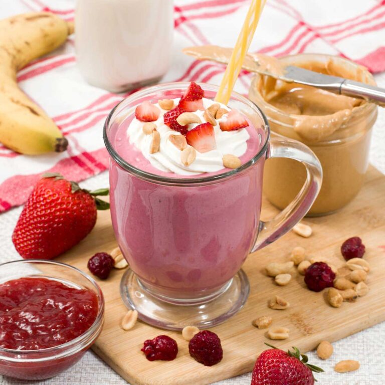 High protein peanut butter and jelly smoothie with peanuts and strawberries on top.
