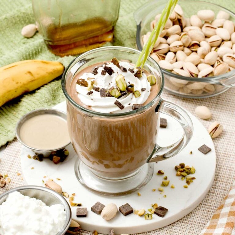 A pistachio chocolate protein smoothie with cottage cheese, banana, and tahini with a straw.