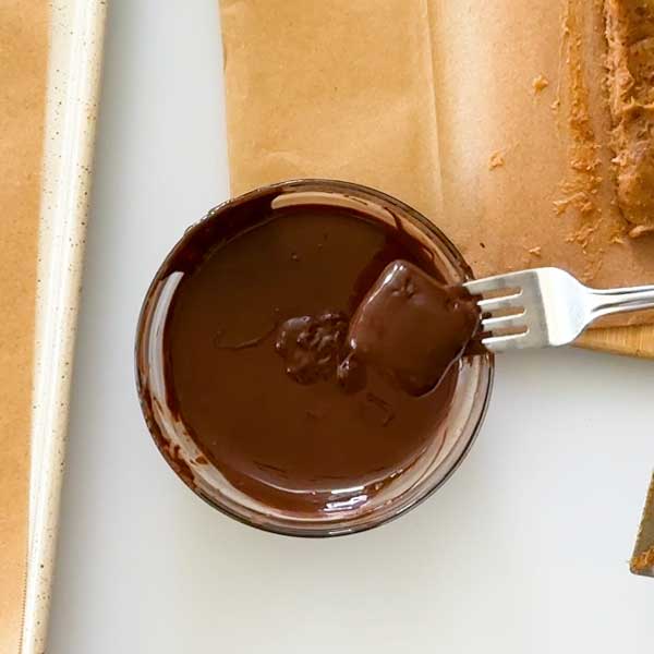 Dipping the date caramel in the melted chocolate.