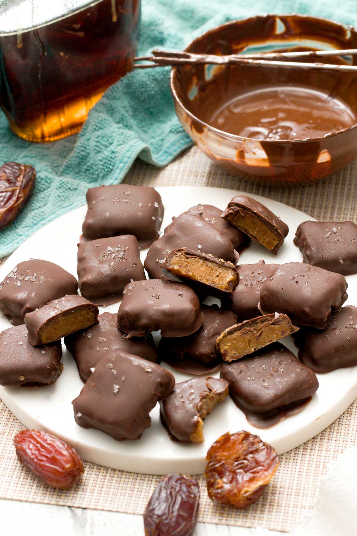 A batch of chocolate covered caramels with sea salt on top.