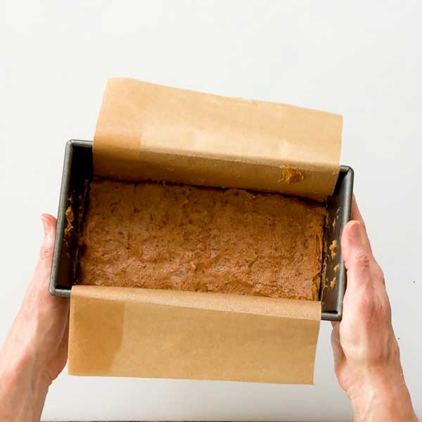 The baked caramel mixture pressed into the bottom of a bread pan on parchment paper.