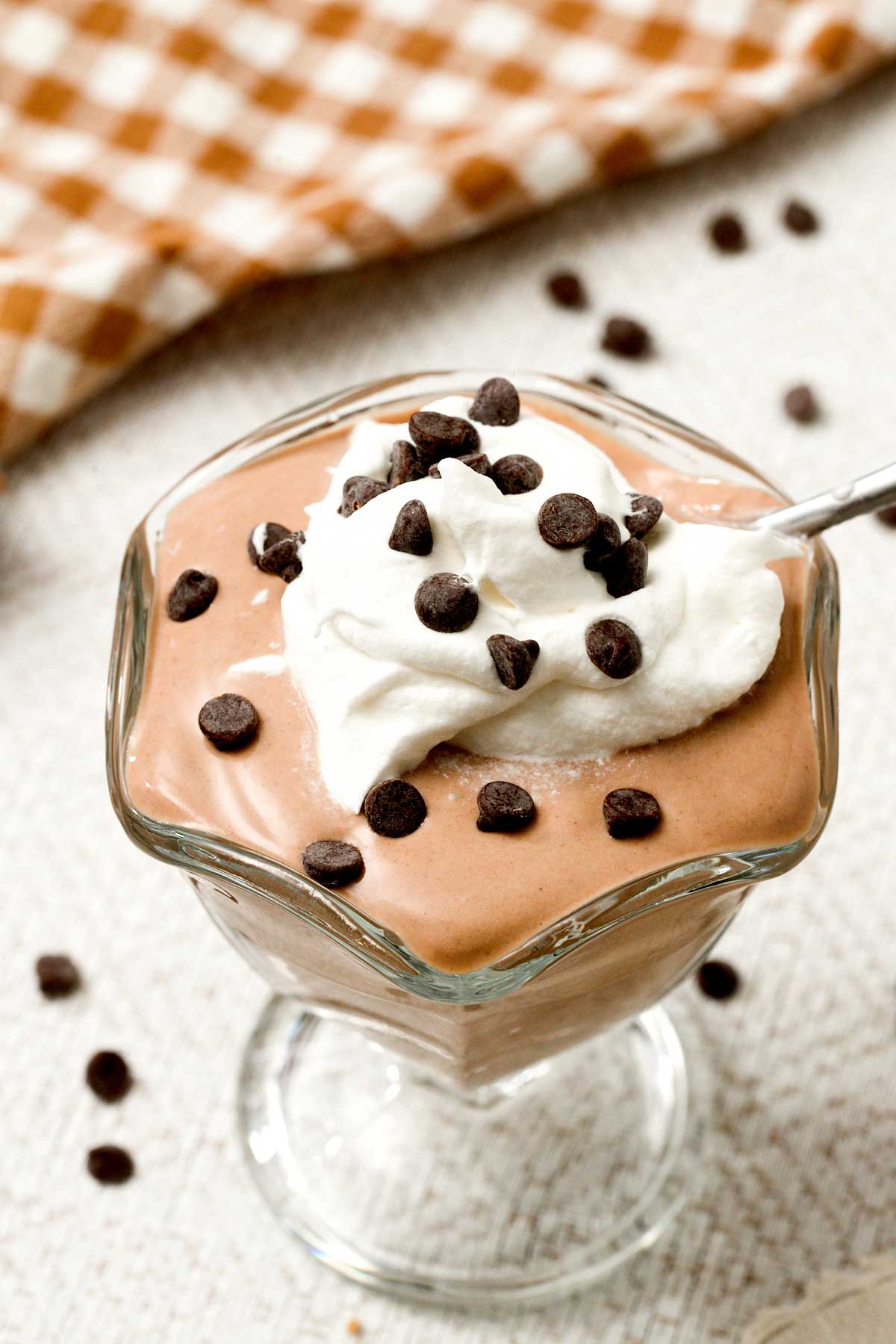 A bowl of chocolate greek yogurt with cream and mini chocolate chips on top.