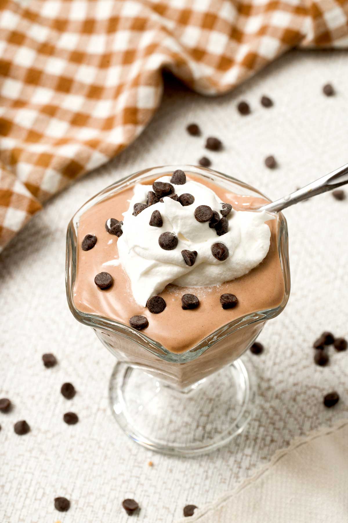 A bowl of high-protein chocolate yogurt with whipped cream and mini chocolate chips on top.