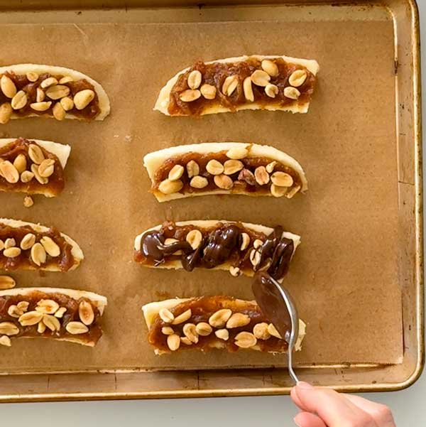 Drizzling the melted chocolate over the peanuts.