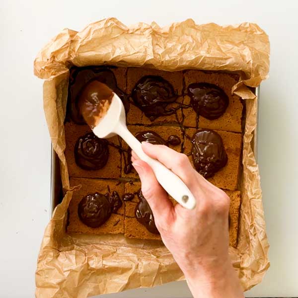 Pouring melted chocolate over the bottom layer of graham crackers.