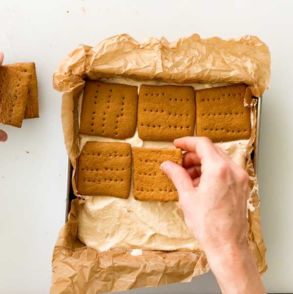Adding the top layer of graham crackers to the cottage cheese ice cream layer.
