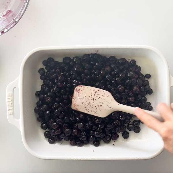 Spreading the blueberry filling in the baking dish with a spatula.