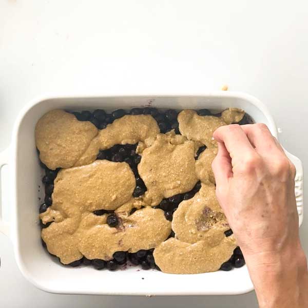 Sprinkling turbinado sugar on top of the cobbler batter.