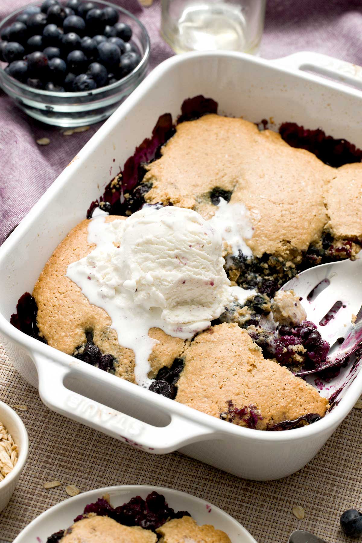 Gluten-free blueberry cobbler made with oat flour with a scoop of ice cream on top.