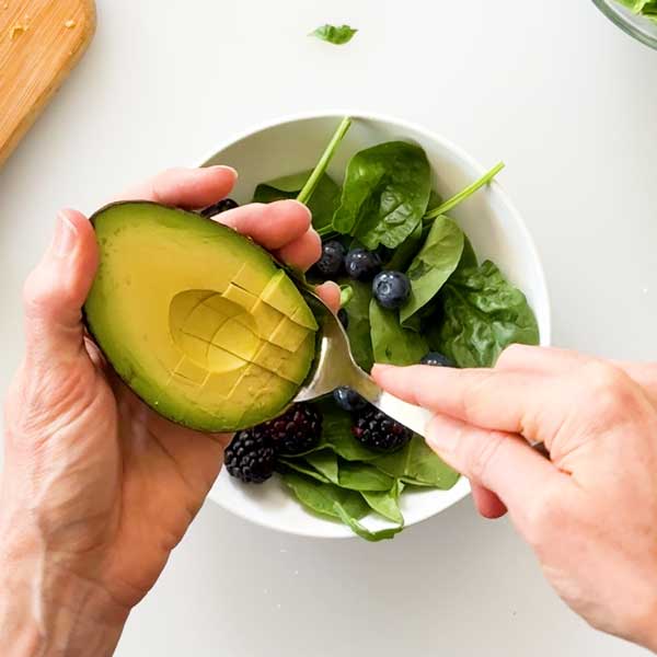 Adding the sliced avocado to the salad.