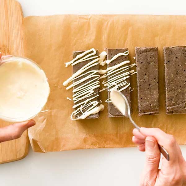 Drizzling the melted white chocolate over the blueberry protein bars.