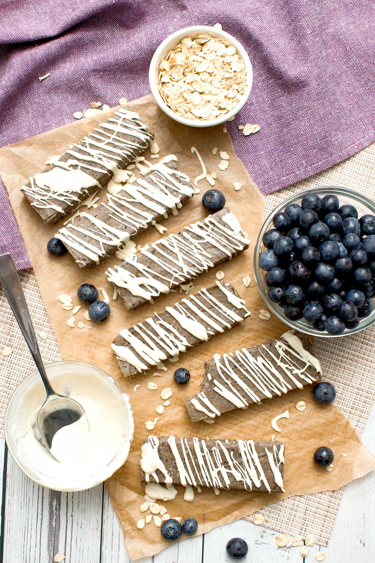 A batch of blueberry protein bars with a white chocolate drizzle on top.