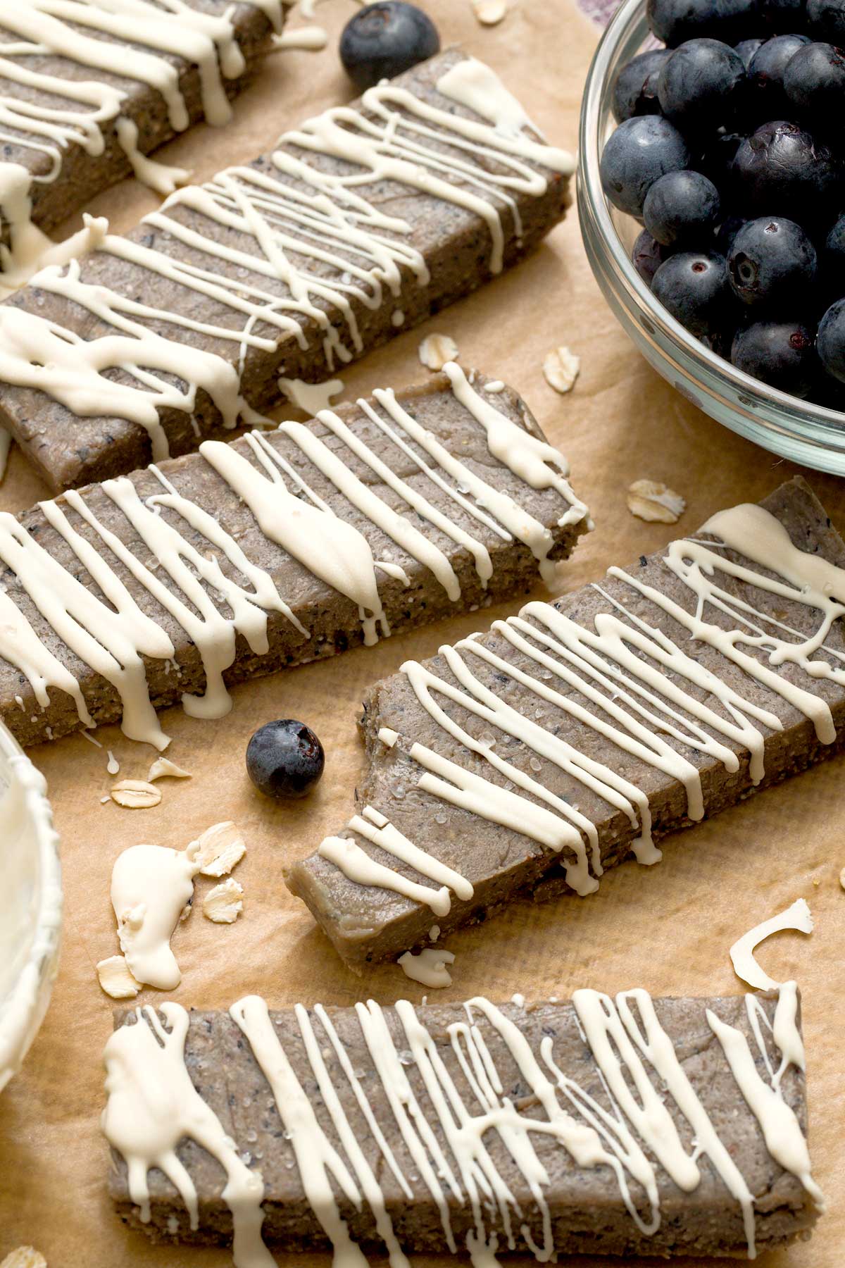Gluten-free oat flour protein bars with blueberries and a white chocolate drizzle on top.
