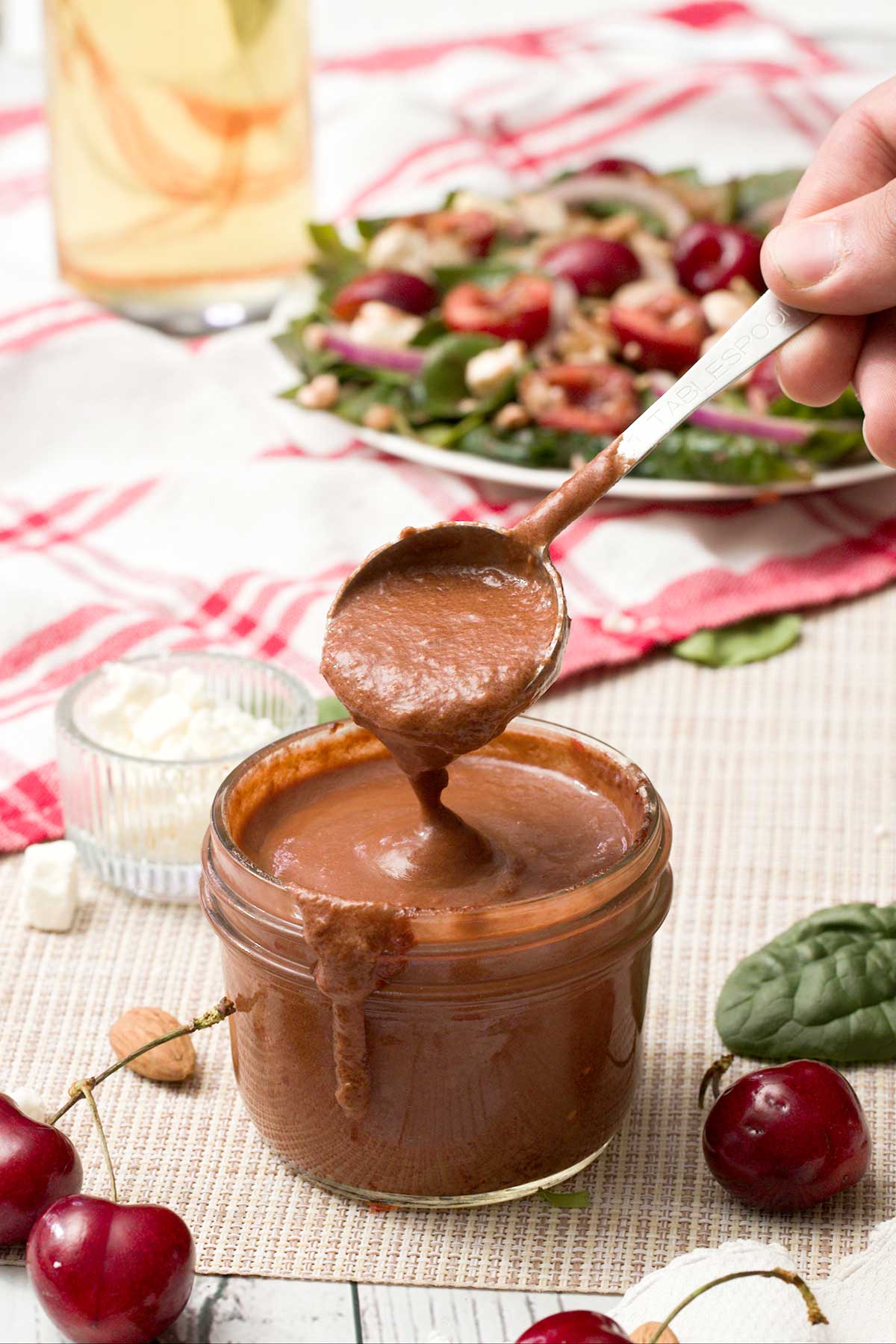 A small jar of cherry balsamic vinaigrette with fresh cherries.