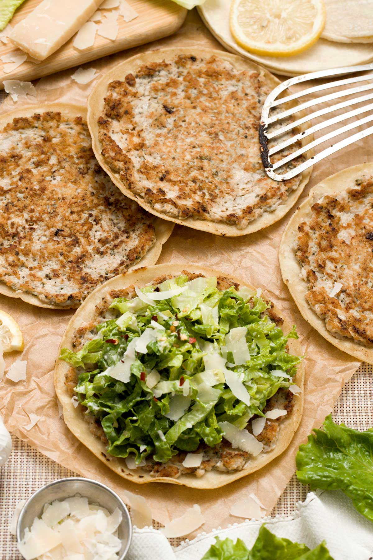 An open face chicken caesar smashed taco with caesar salad.