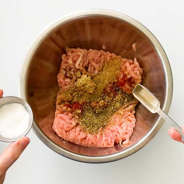 Adding all the seasonings to the chicken smash taco meat.