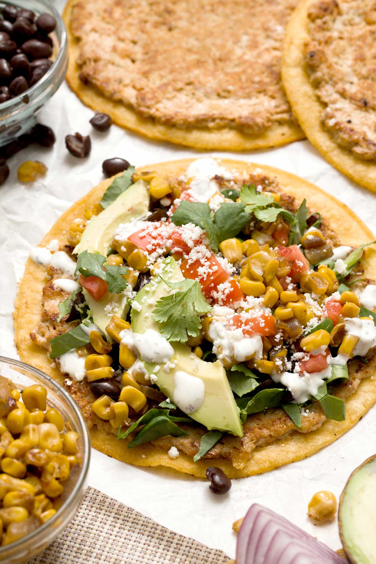 And open chicken smashed taco with Mexican street corn, avocado, and cilantro lime cream on top.