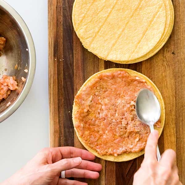 Spreading the chicken meat mixture onto the tortilla with the back of a large spoon.