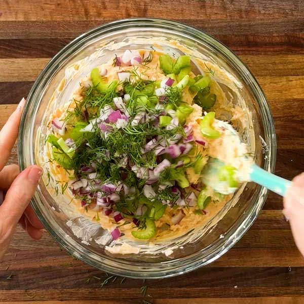 Adding all the chopped salad ingredients to the mixing bowl.