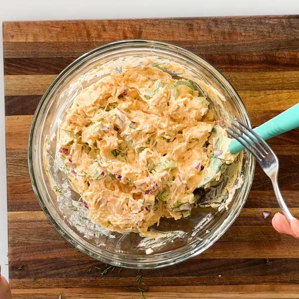 Mixing all the salad ingredients together in a mixing bowl.