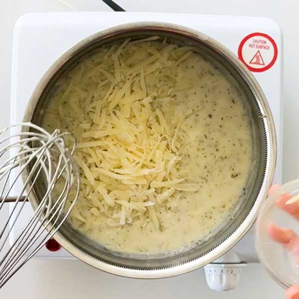 Adding the shredded Parmesan cheese to the sauce in the skillet.
