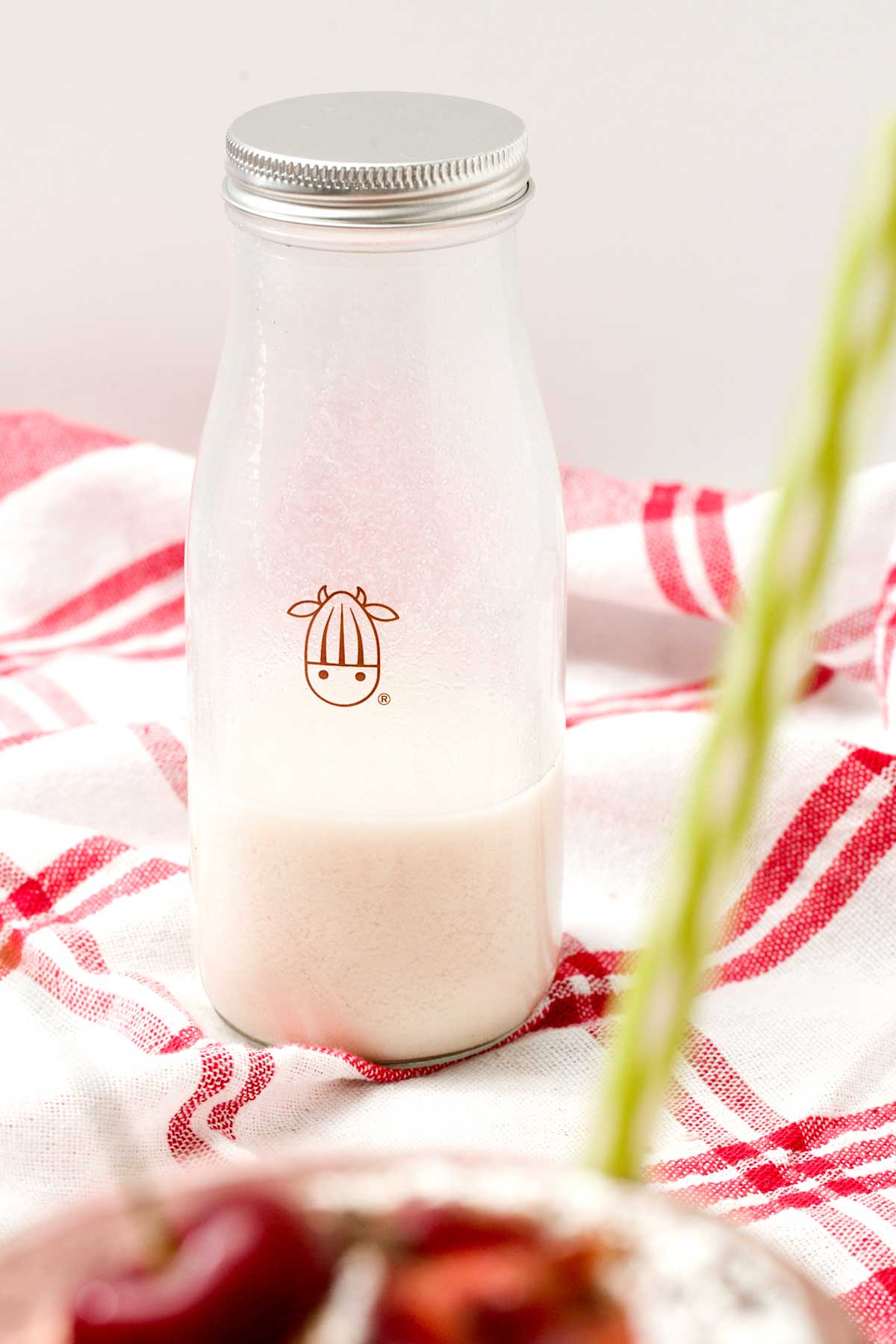 A glass bottle of almond milk made with the almond cow.