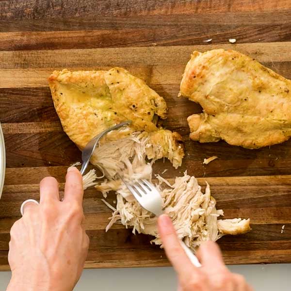 Shredding the chicken with two forks.