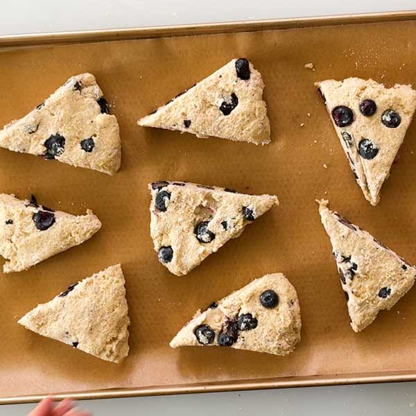 Spacing the scones out on the parchment paper on the baking sheet.