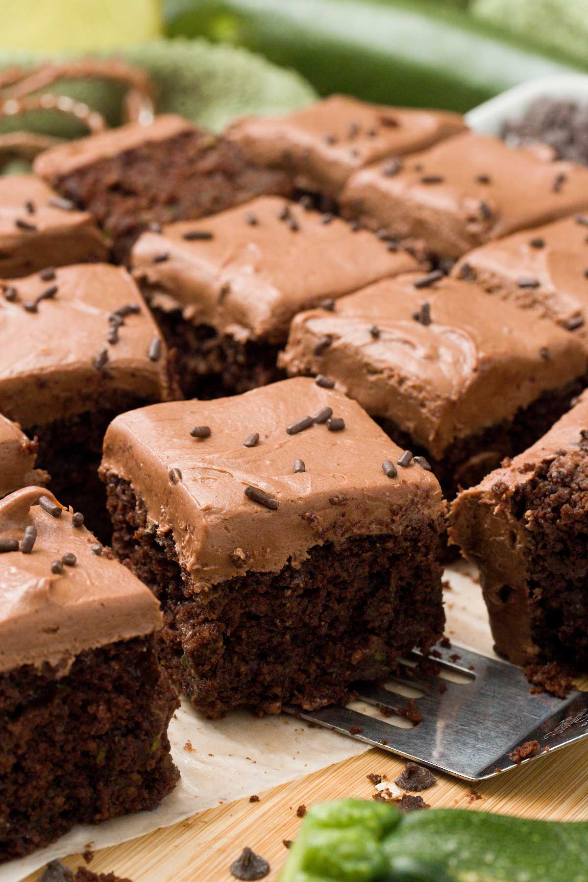 A close up of gluten-free chocolate zucchini cake with chocolate cream cheese frosting and sprinkles on top.