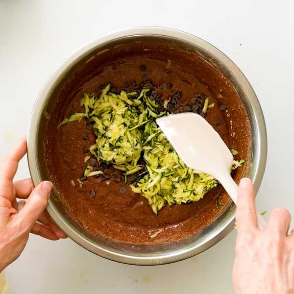Folding in the shredded zucchini and mini chocolate chips to the cake batter.