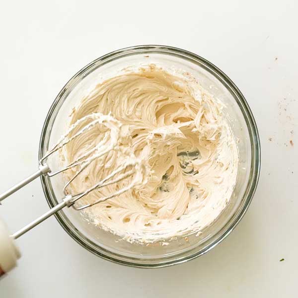 Creaming together the cream cheese and butter and a mixing bowl.