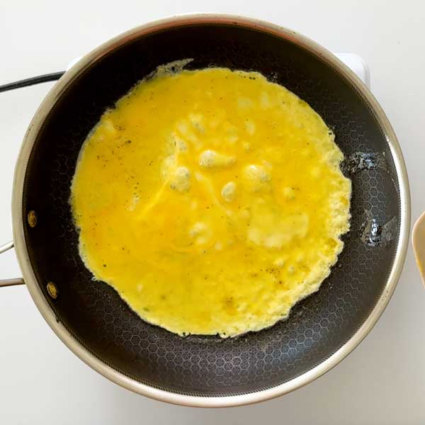 Spreading the egg in the bottom of the skillet.