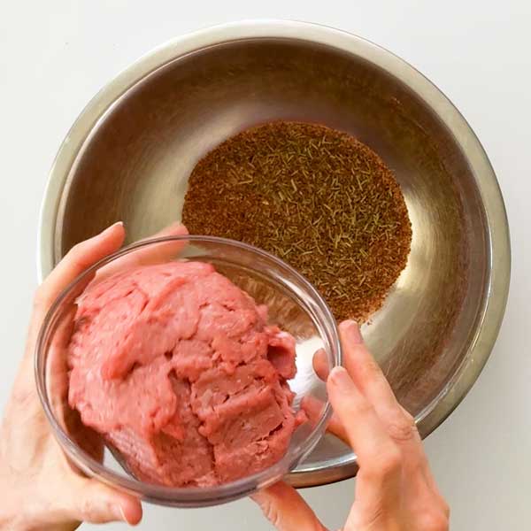 Adding the ground turkey to the dry seasonings in a mixing bowl.