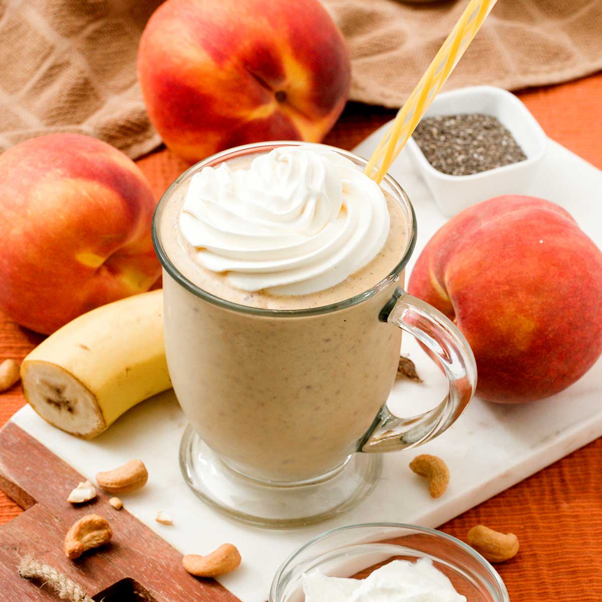 A high protein peaches and cream protein smoothie in a glass with a straw.