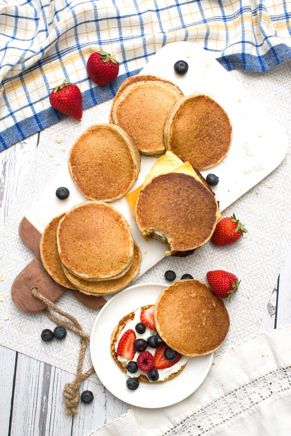 Gluten-free protein pancake sandwiches with oat flour and filled with cream cheese and berries, and sausage, eggs, and cheese.